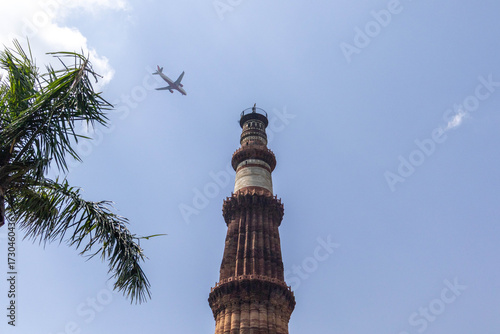 Φωτογραφία Majestic Qutub Minar soaring under clear blue sky, framed by green foliage in Delhi, India – UNESCO World Heritage Site and famous historical landmark