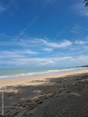 Canvas Print Wide angle view of a sandy beach with clear blue sky and scattered clouds, calm