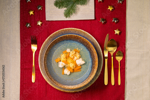 Christmas dinner table setting with soup bowl and festive decorations