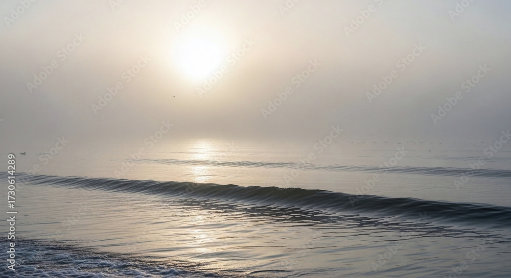 Obraz premium A serene coastal sunrise as the golden sun gently breaks through the morning mist, its soft light whisking across the tranquil ocean waves, creating a peaceful and ethereal seascape