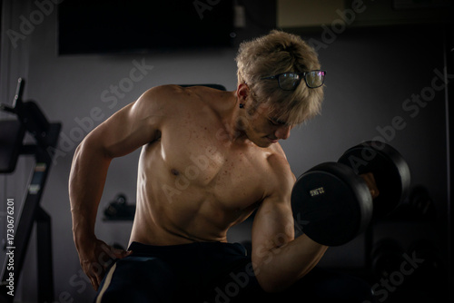 Athletic shirtless handsome young man, muscular young men are exercising with weights in a gym.
