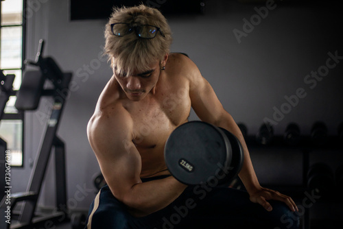 Athletic shirtless handsome young man, muscular young men are exercising with weights in a gym.

