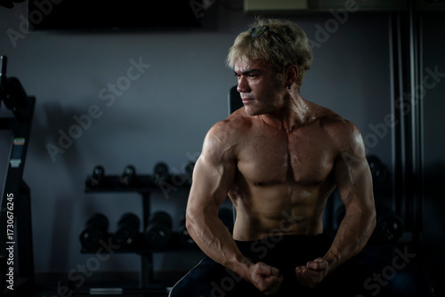 Athletic shirtless handsome young man, muscular young men are exercising with weights in a gym.
