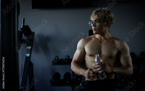 Athletic shirtless handsome young man, muscular young men are exercising with weights in a gym.
