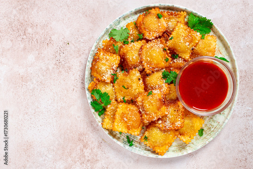 fried ravioli with parmesan cheese, served with red sauce and garnished with herbs, on a light background, no people,