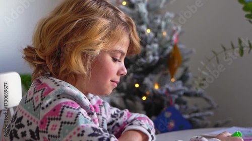 Child writing letter to Santa Christmas New Year holiday, cosy home Christmas decoration and lights, girl dreaming drawing colorful pencils preparing gifts presents for family, boy wishing Santa Claus
