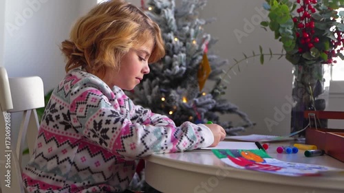 Child writing letter to Santa Christmas New Year holiday, cosy home Christmas decoration and lights, girl dreaming drawing colorful pencils preparing gifts presents for family, boy wishing Santa Claus