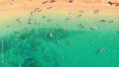 Vue aérienne verticale d’une plage aux vagues turquoise avec des personnes qui se baignent