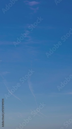 Timelapse of passenger plane flying in the blue sky, fast transport leaves behind a white contrail trail. A trace of condensation trails or vapor trails, the aircraft engine exhaust.