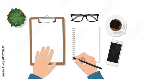 A creative person is writing a list on a notepad while working at their desk with a cup of coffee.