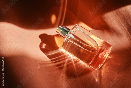 A pink perfume bottle on a soft reddish background.