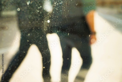 Abstraktes Motiv mit Rückenansicht von zwei in schwarz gekleideten jungen Männern auf Gehweg in Stadt bei Sonne am Abend im Sommer