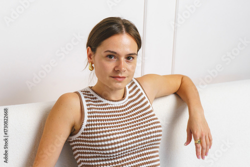 Studio shot: stylish young woman posing sitting on a white sofa Free Download Studio shot: stylish young woman posing sitting on a white sofa - GFXLoad
