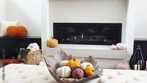 Burning fireplace with cozy autumn decor display in a beautiful warm modern living room. Slow panning motion.