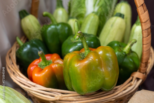 Colorful assortment of fresh vegetables including bell peppers, zucchini, and leafy greens arranged in a woven basket, showcasing vibrant colors and natural textures for healthy eating