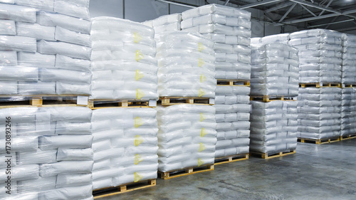 Large stacks of white bags, neatly stacked on wooden pallets and wrapped in transparent plastic.