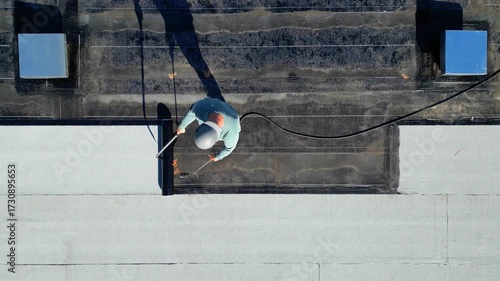 Roofer applying torch to bitumen membrane on torch down roof