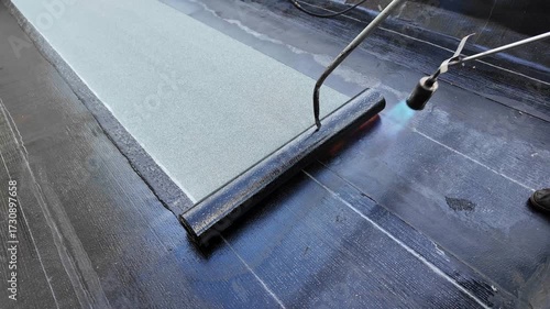 Roofer applying torch to bitumen membrane on torch down roof