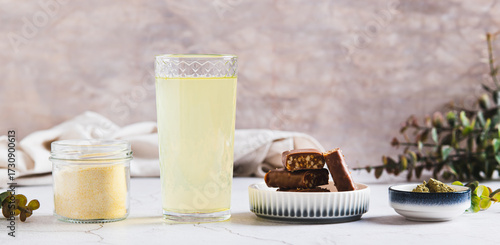 Matcha protein drink in glass, powder and protein bars on table web banner