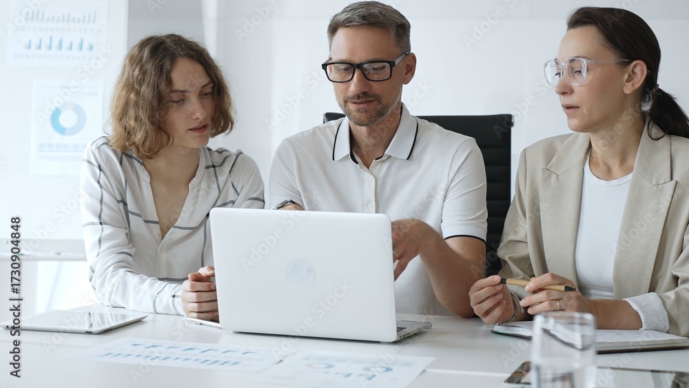 Obraz premium Professional team analyzing data on laptop, sharing insights during collaborative office meeting, highlighting workplace synergy and strategic planning. Business people concept