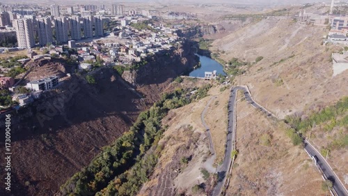 Aerial view of a hydroelectric dam in the middle of a large canyon. Residential and industrial zones on either side of the canyon.