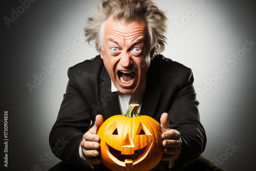 screaming, mad man with wild hair and a wide-eyed expression holding a smiling, carved jack-o'-lantern, a hilarious and energized halloween portrait. Helloween 
