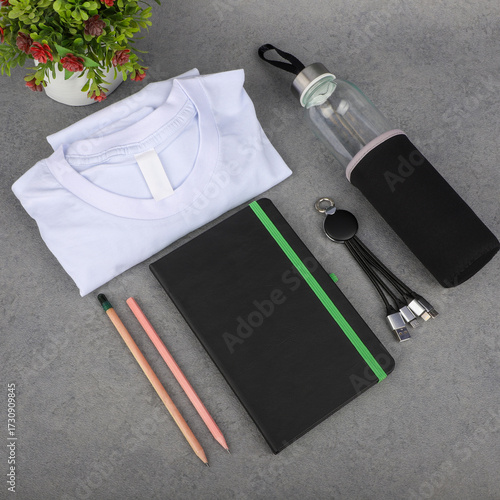 Minimal Office Desk Essentials With Notebook, Shirt, Water Bottle, Pencils, and Cables