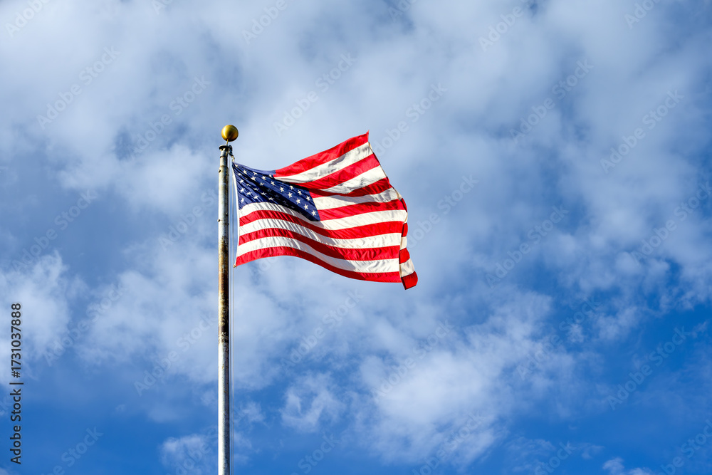 Obraz premium Celebrate independence day, 4th of July, with American flag flying against a sunny blue sky with white puffy clouds, Grand Canyon National Park, Arizona 