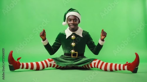 Elf sitting on green background wearing green outfit with red and white striped leggings and shoes christmas elves green screen video