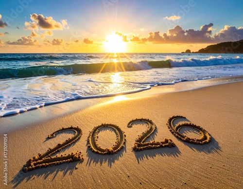 波打ち際の砂浜に書かれた2026の数字を朝日が照らしている