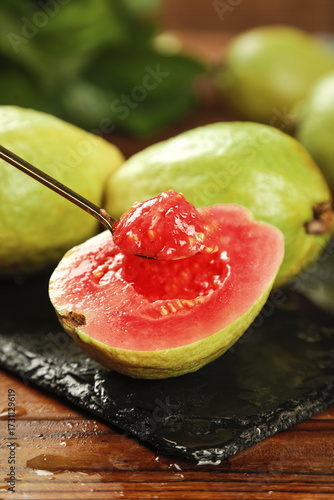 Fresh Red Guava Fruit Cut Open Showing Soft Creamy Pink Flesh with Spoon on Slate Board