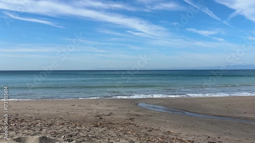 穏やかに波が割れている真夏の青い空と白い雲を背景にしたビーチ