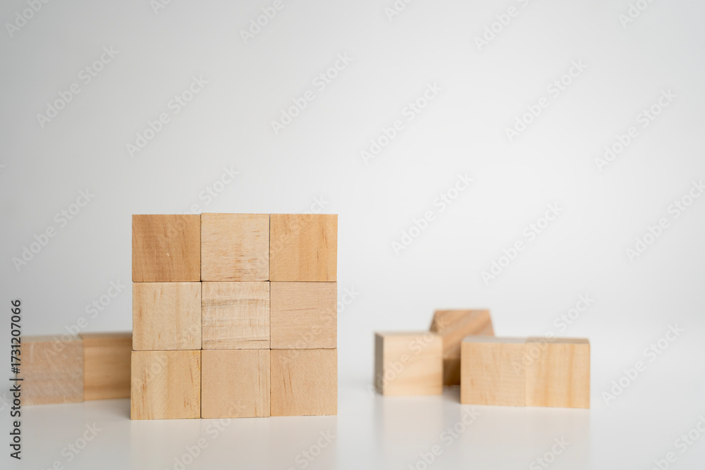 Obraz premium Wooden cubes arranged in solid square block on white background symbolizing structure, stability, order
