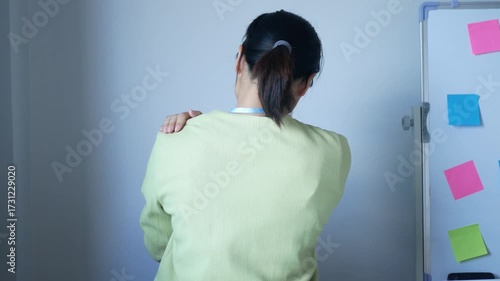 A young Asian woman feels pain in her neck muscles. Tired from sitting and working at the office all day. The concept of office syndrome.	