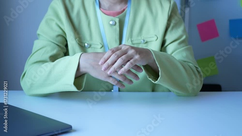 A young Asian woman working at the office feels pain in her wrists from typing from a laptop for a long time. Pain and numbness in the wrist Health care and medical concept.	