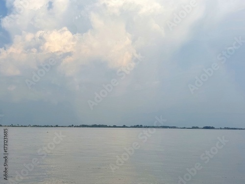 Calm water reflects a cloudy sky over a distant horizon