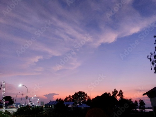 Vibrant sunset sky over silhouetted trees and landscape