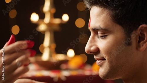 indian woman applying tilak to man's forehead during festival