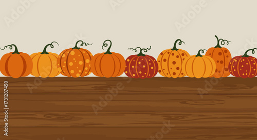 A row of pumpkins with varying designs sit atop a wooden surface