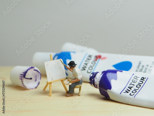 Mini toy of action figure at outdoor with blurred background. Toy photography concept design. Minifigure of professional painting character with water colour and canvas.