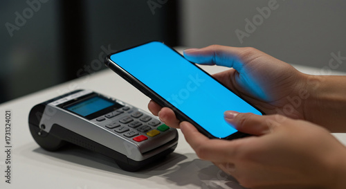 A person makes a contactless payment by holding a smartphone over a credit card terminal. Concept of NFC and mobile payment technology.