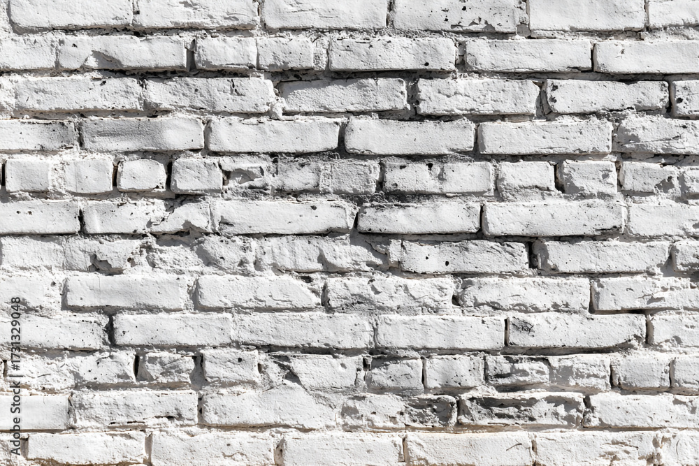 Fototapeta premium An old weathered brick wall painted white showcases its rustic texture and character