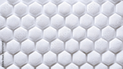 An abstract macro view of a clean white surface with a repeating geometric pattern of textured hexagons forming a honeycomb structure