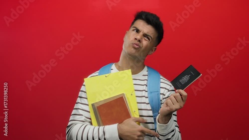 Man holding canada passport wearing striped shirt with yellow folder in front of red background portraying travel and identity concepts.