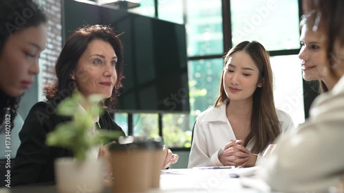 Businesswoman team brainstorming in contemporary workplace, female professionals discussing strategy, teamwork and leadership in office environment with natural light and casual business atmosphere.