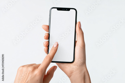 A woman with a neat manicure holds and touches a modern smartphone with a blank white screen isolated on a white background