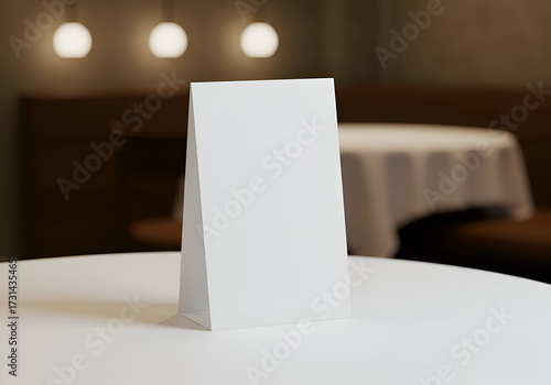 Empty table tent on a round table in a restaurant setting. Blank sign positioned for restaurant menu or promotional display.