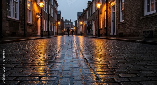 Cobblestone reflections: urban streetscape glowing with lamplight after rainfall at dusk