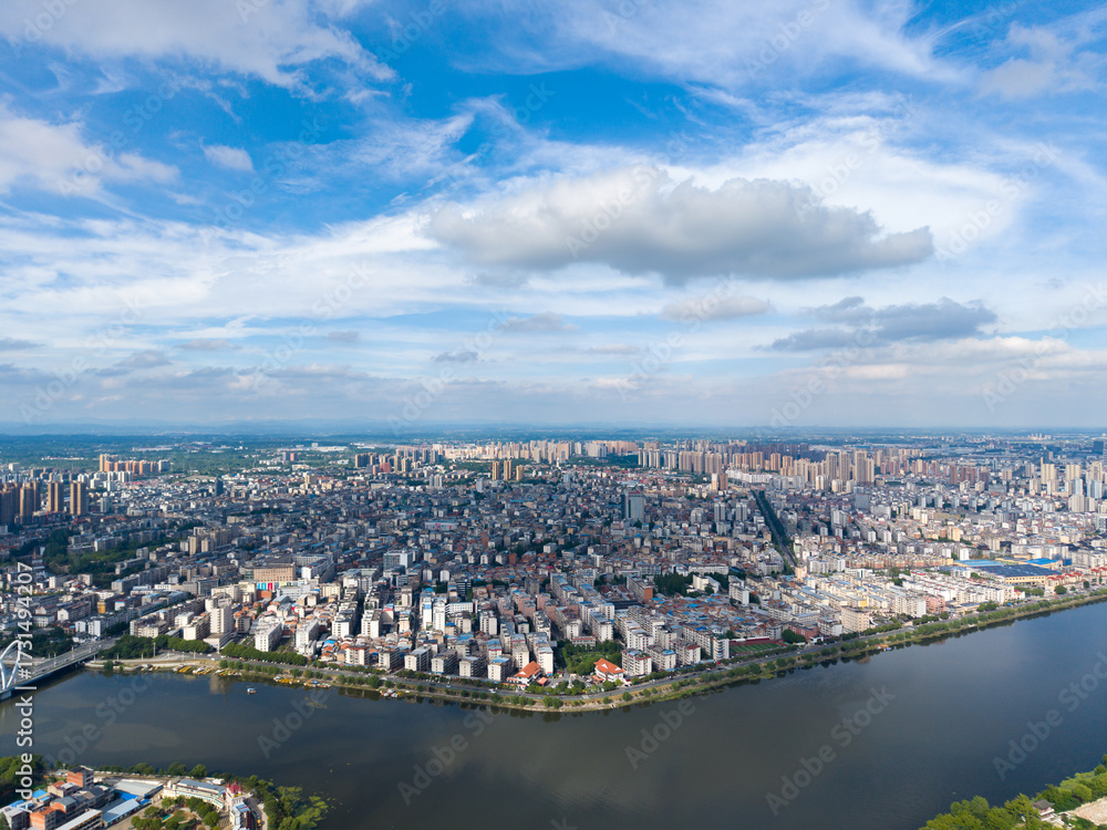 Fototapeta premium Suizhou City Hubei Province China cityscape spreads across the horizon under a cloudy blue sky showcasing buildings and a river.