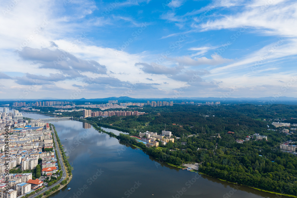 Obraz premium Suizhou City Hubei Province China shows buildings lining a river and green trees under a sky with clouds.